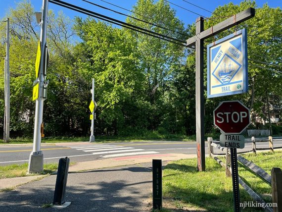 Paved rail trail ending at crosswalk with trail sign