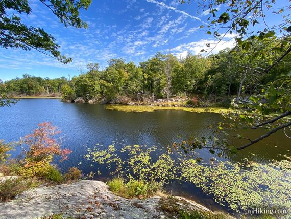 Pretty lake with rocks in the foreground and green trees on the shore