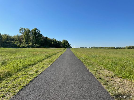 Paved trail with fields on either side