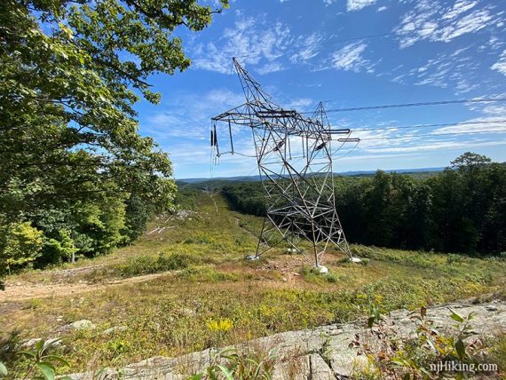 Large power tower and lines with a view of hills beyond