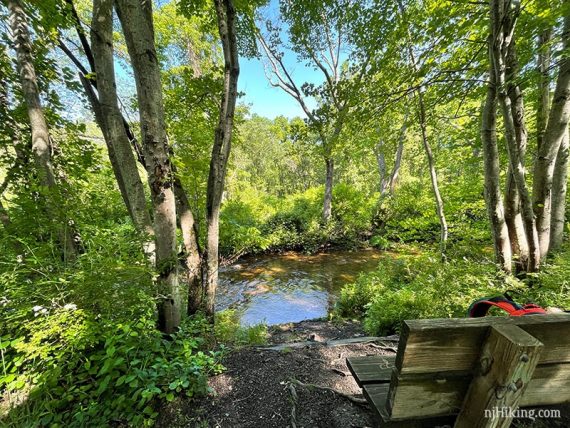 Bench in foreground with backpack with river behind