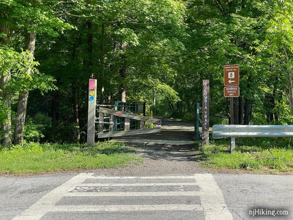 Wooden gate and signage at a rail trail street crossing.