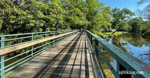 Bike rider on a long rail trail bridge over a river