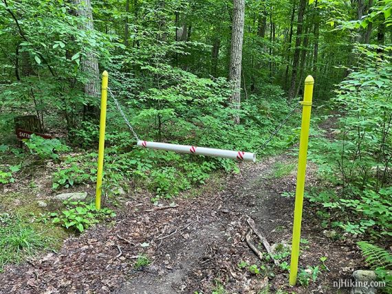 Yellow posts with a chain blocking trail access