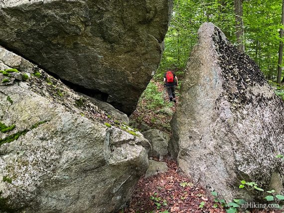 Hiker past a large split rock