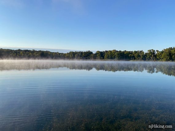 Low layer of fog across a bright blue clear lake