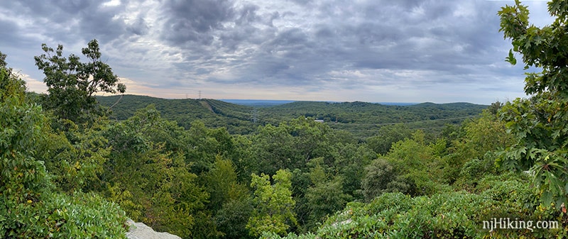 Wide view from an overlook of green hills and power lines in the distance