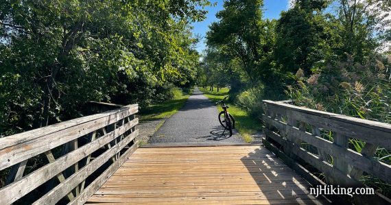 Bike on a paved rail trail after a wooden bridge