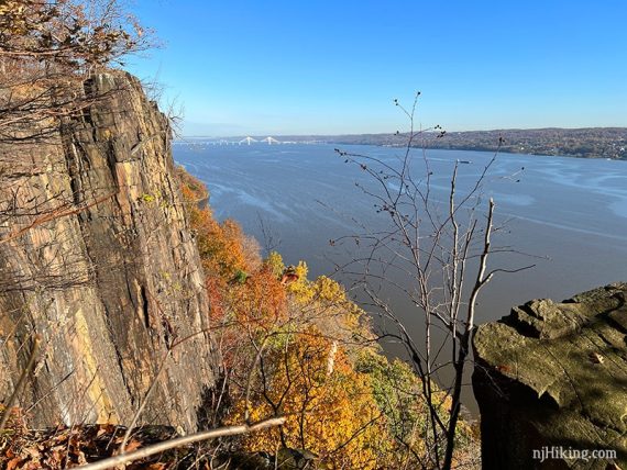 Steep cliff with fall foliage below next to the Hudson River.