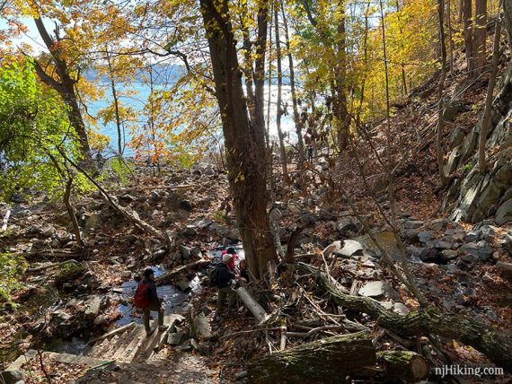 Hikers around stream and stone step ruins.