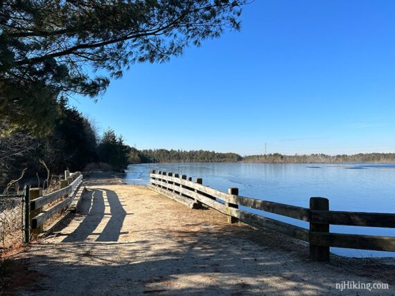 Sand road and fence next to a reservoir.