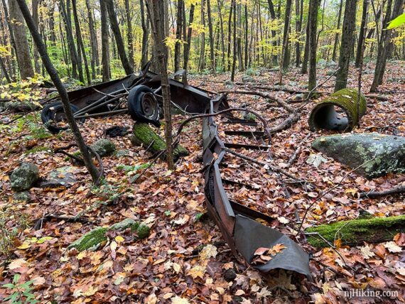 Long rusted metal trough with wheels abandoned in the forest