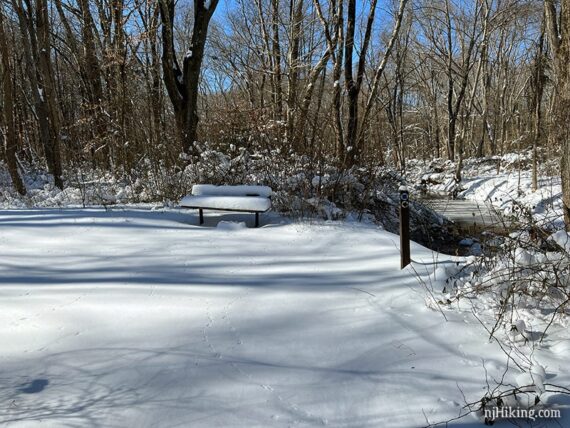 Snow covered bench by a river