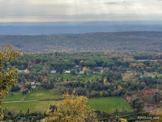 Zoom into houses and fields in a valley seen from a ridge top