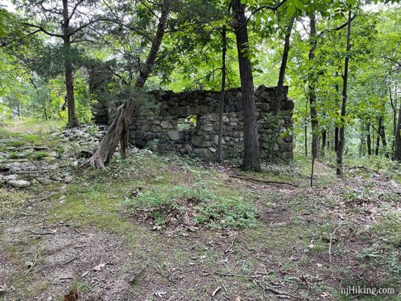 Ruins of a small stone cabin along a trail.