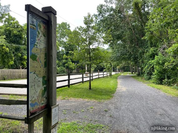 Map sign for Barnegat Branch Trail near a fenced gravel lot at Country Lane.