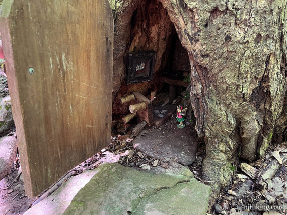 Fairy house with a large wooden door in a tree trunk.