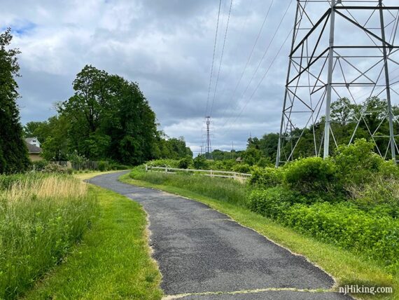 Wide paved rail trail curving around a tower.