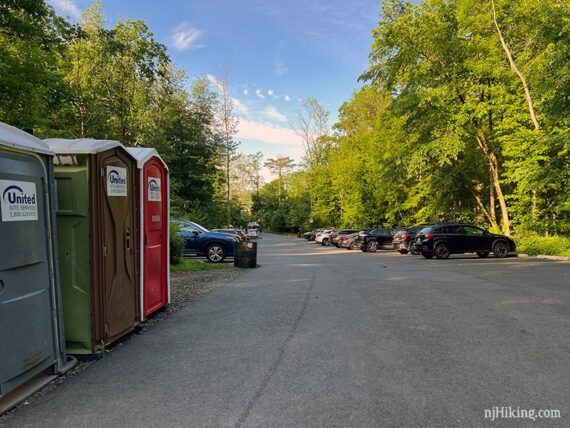Large paved parking lot with a row of portable toilets.