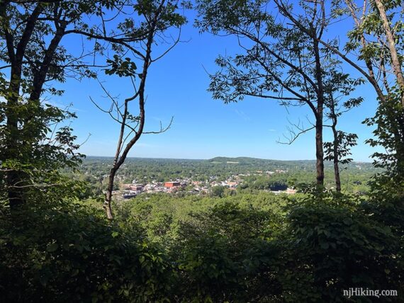 View over a city in a valley surrounded by trees.