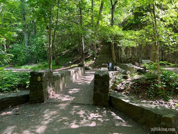 Large stone bridge with a yellow trail marker and stone steps seen beyond it