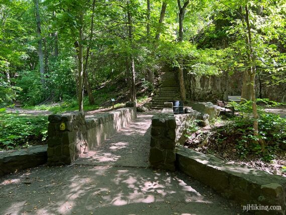 Large stone bridge with a yellow trail marker and stone steps seen beyond it.