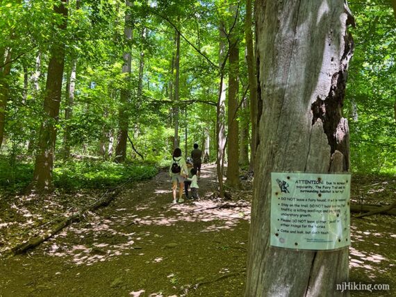 Family hiking the fairy trail with a sign on a tree.