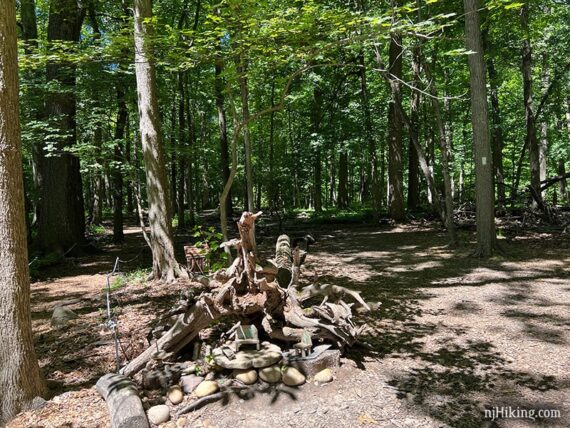 Fairy house nestled in a fallen tree stump with a path on either side.