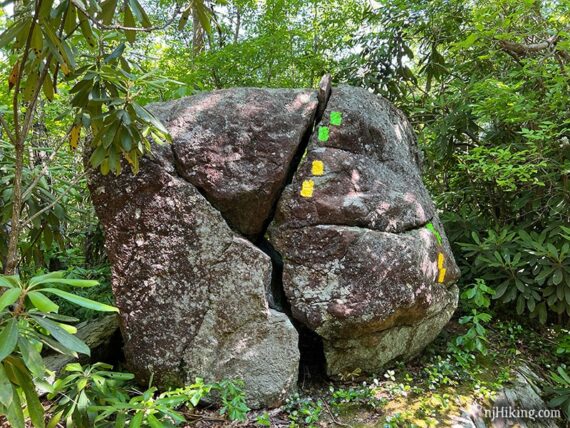 Large squarish boulder with a jagged split down the center and yellow and green markers