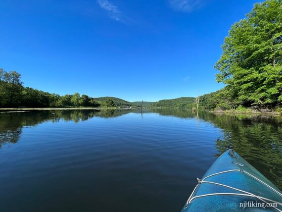 Green hills and flat blue water seen from a kayak.