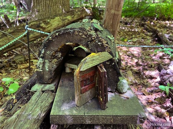Hollow half of a log with a door and furniture inside.