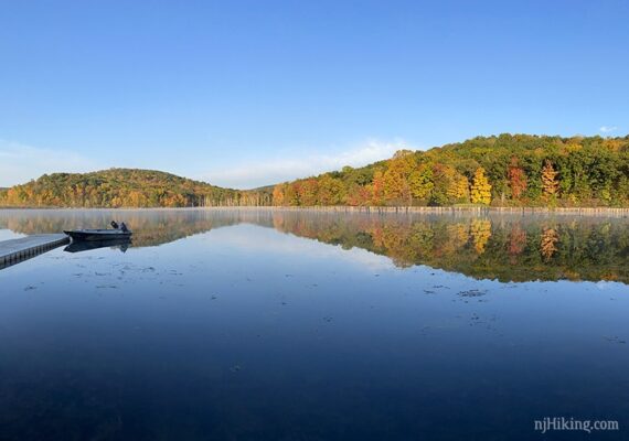 Boat at a dock with hills in the distance reflected in the water