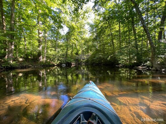 Kayak on a shallow river with rocks visible in the water.