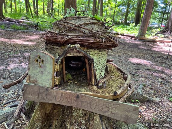 Round fairy house made out of a hollow log with a wooden door.