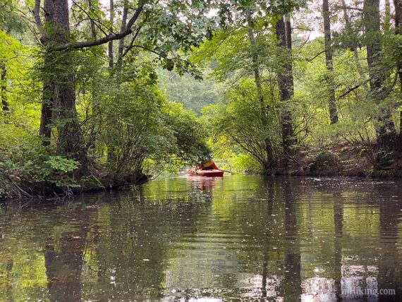 Kayaker in a narrow opening in land at the entrance to a cove.