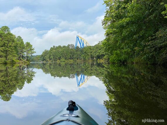 Nitro roller coaster peeking above the trees seen from a kayak on a lake.