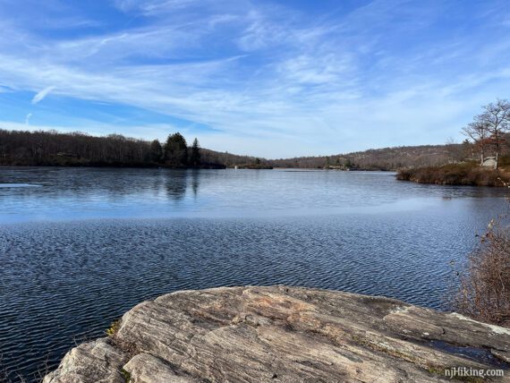 Rocky outcrop on a lake with a bright blue sky above.