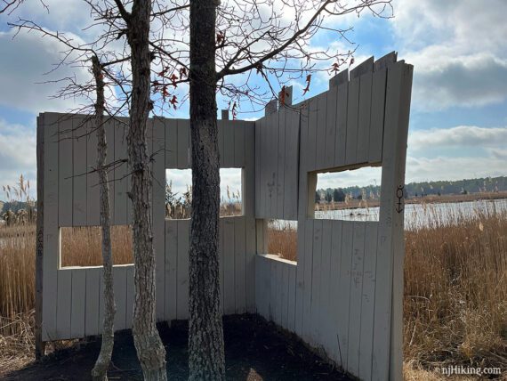 Wooden wildlife blind with marsh grass in front of it.