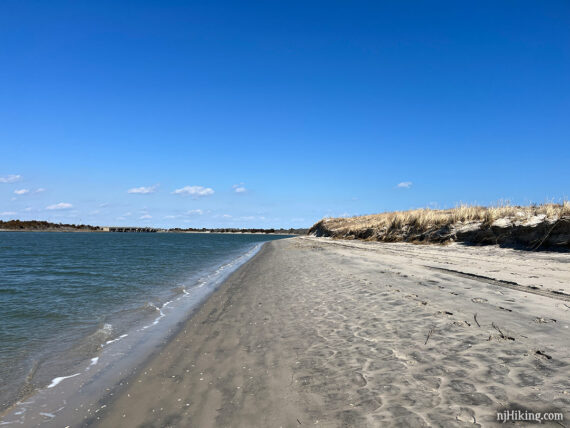 Blue bay, beach, and grass covered sand dunes.