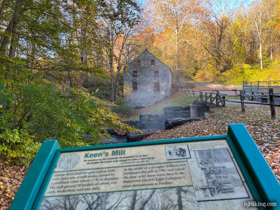 Interpretive sign about Keen's grist mill with the mill seen behind it. 