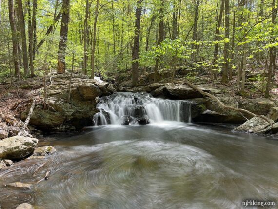 Water cascading over rocks into a pool of water.