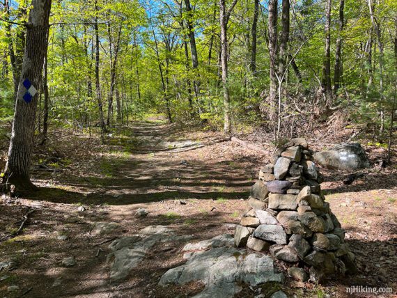 Large stack of rocks at a trail intersection.