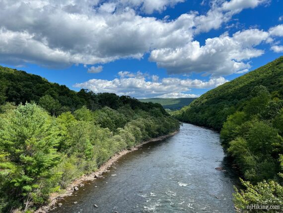 Lehigh River with green hills on either side and fluffy clouds in a blue sky.