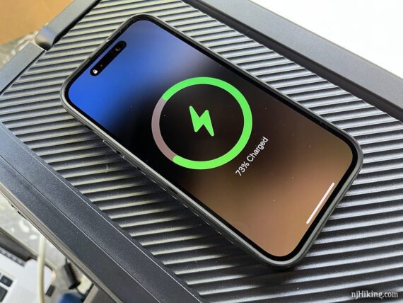 Phone showing a charging symbol while sitting on a wireless charging pad.