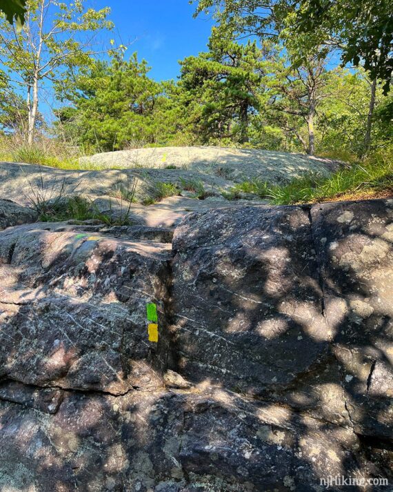 Trail markers painted on a large steep rock face.