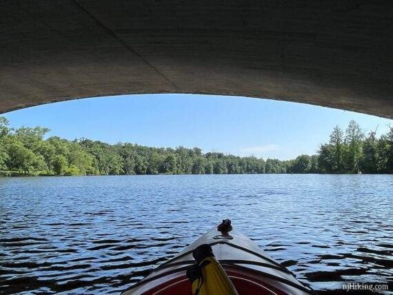 Kayak floating in the shade of a bridge underside.