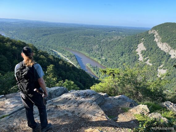 Hiker on a flat rocky area overlooking Mt. Minsi and the Delaware River.