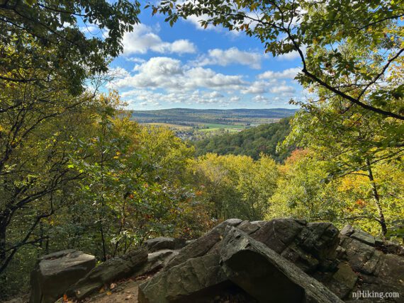 View of a valley framed by trees and a rocky outcrop.