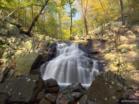 Waterfall the rocks in the foreground and yellow foliage overhead.