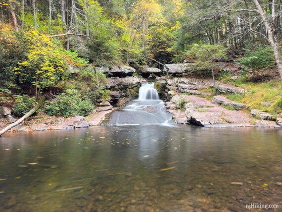 Water falling over rock slabs into a wide shallow pool.